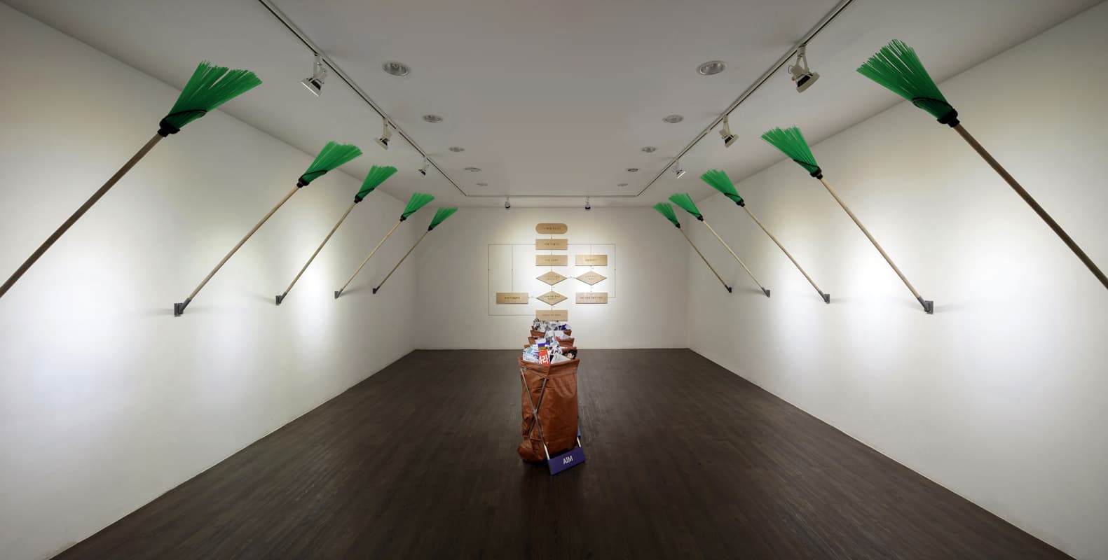 이슈를 대하는 우리의 자세_버린 것, 2017, 장빗자루(10EA), 철재 쓰레기통과 마대, 아크릴, 시트지, 각종 쓰레기(5EA),                                나무합판에 레이저각인, 마스킹테이프, 시트지, 가변설치