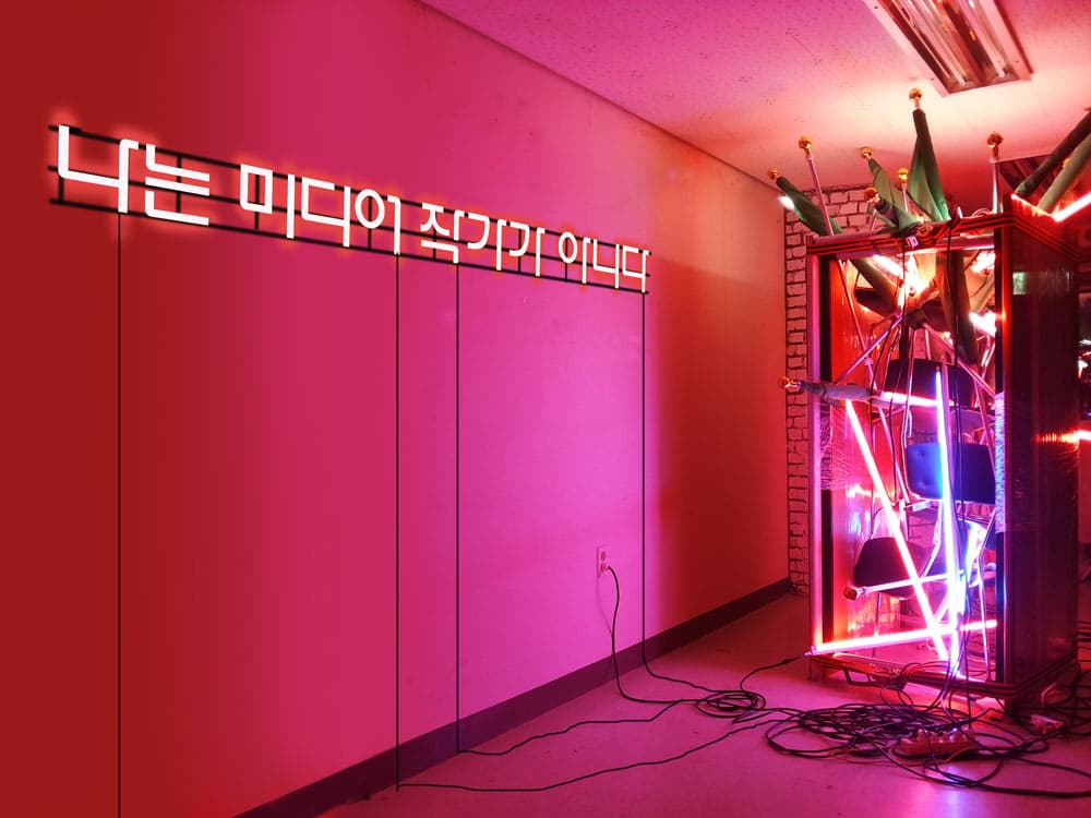 권승찬, 나는 미디어작가가 아니다!,  2015, 가변크기, 테이블, 유리, T5슬림형광등, 네온, 전선, 의자